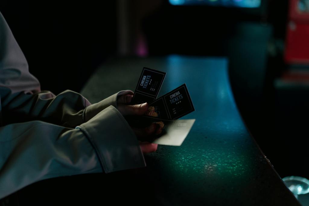 Person with two cinema tickets in their hands in a dark theatre.